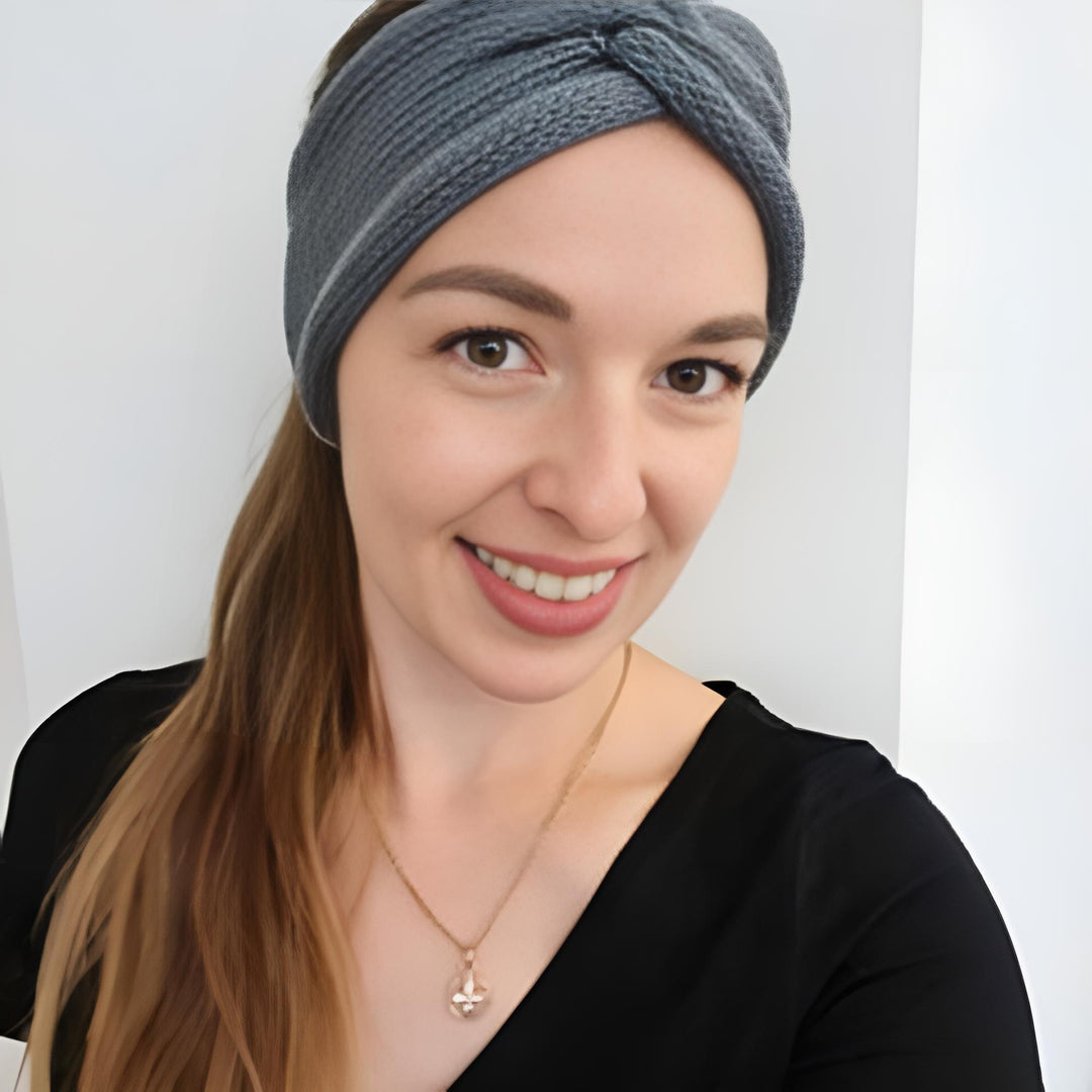 Smiling woman wearing a headband and necklace, posing for a selfie.
