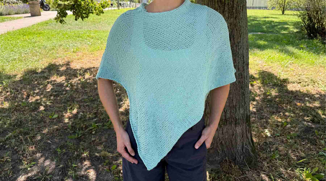 Person in einem wasserblauen gestrickten Poncho.