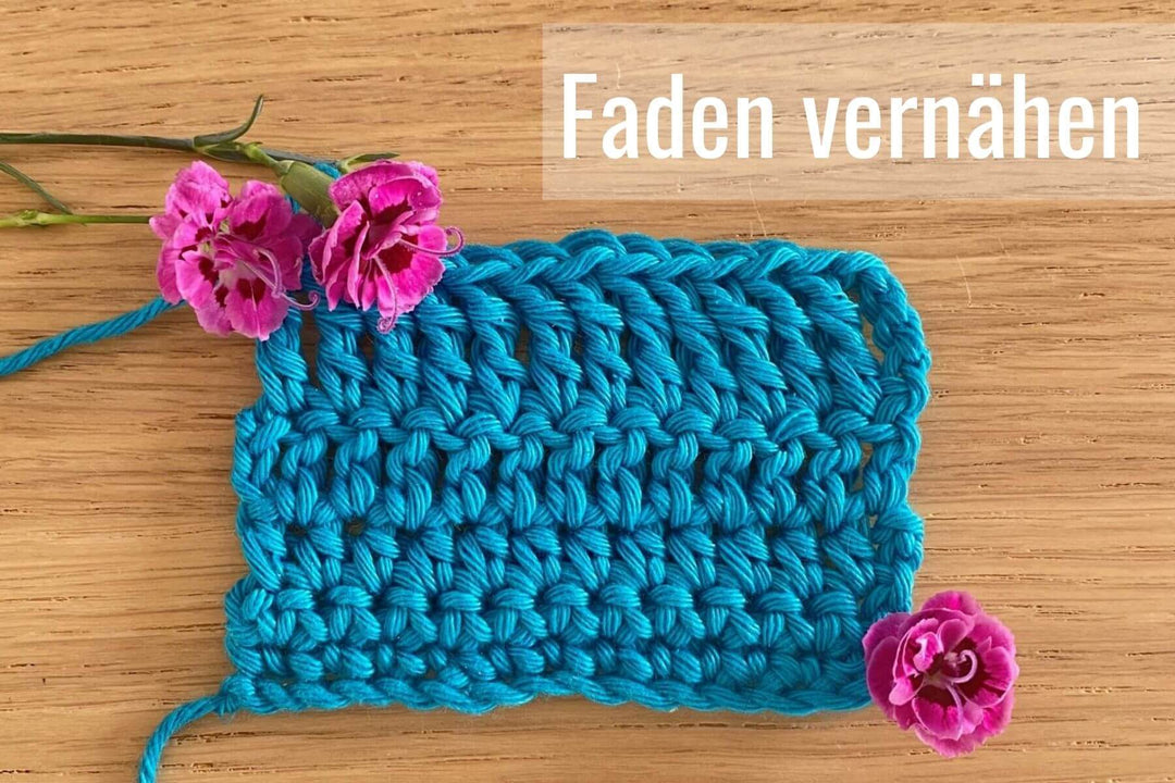 Foto einer gehäkelten Maschenprobe aus blauem Garn mit Text Faden vernähen und drei Blumen.