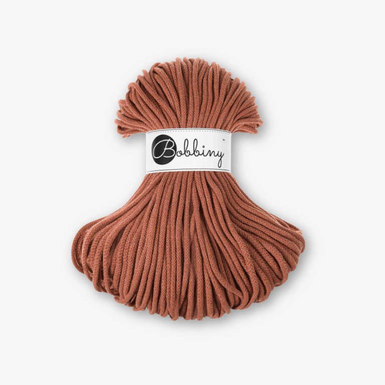 Terracotta Bobbiny Kordel mit Banderole vor grauem Hintergrund.