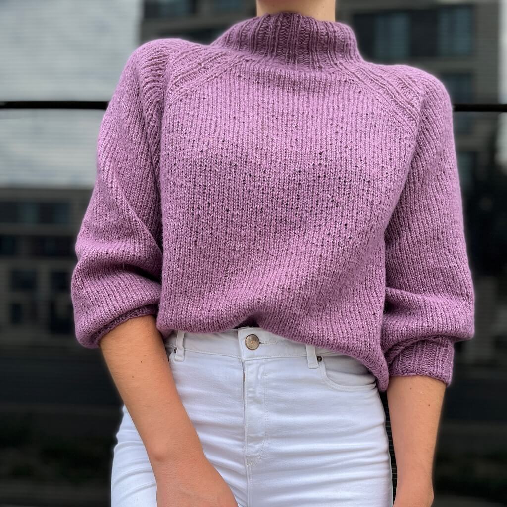 Eine Frau trägt den gestrickten Cashmere Cloud Raglanpullover von Austermann in Lila.